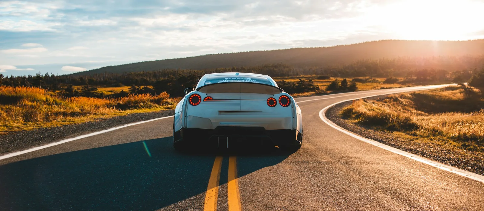 A car on an open road into the sunset